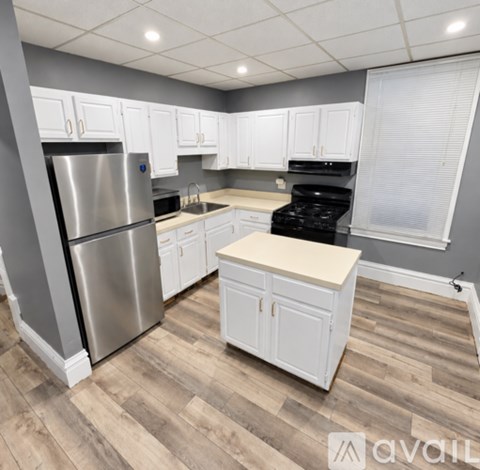 A kitchen with a stainless steel refrigerator, white cabinets, and a wooden island.