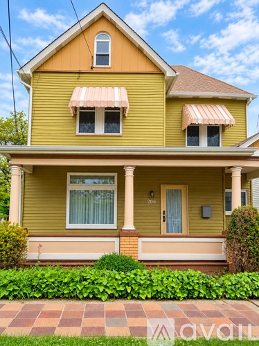 A yellow house with a brown roof and a white door.