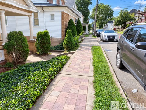 A residential street with a sidewalk and parked cars.