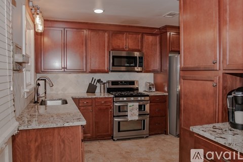 A kitchen with wooden cabinets and a marble countertop.