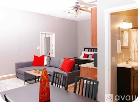 A living room with a grey couch and a red pillow.