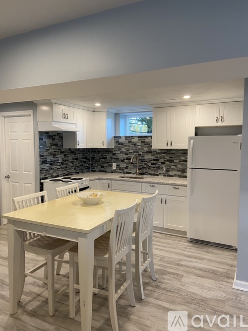 A kitchen with a table and chairs in the foreground and a refrigerator in the background.