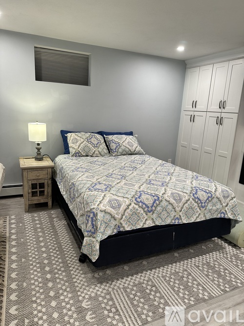 A bedroom with a bed, a nightstand, and a rug.