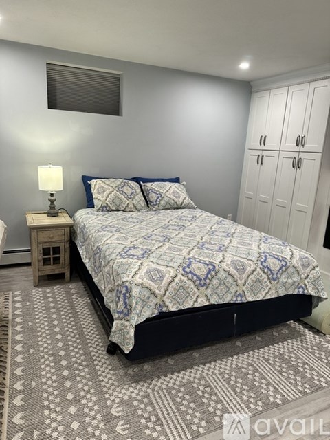 A bedroom with a bed, a nightstand, and a rug.