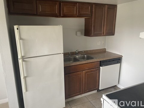 A kitchen with brown cabinets and a white fridge.