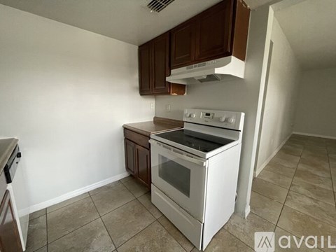 A kitchen with a white stove top oven and brown cabinets.