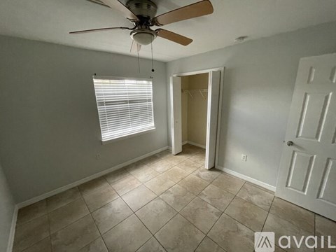 A room with a ceiling fan and a door leading to another room.