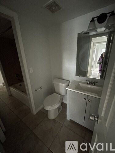 A bathroom with a toilet, sink, and mirror.