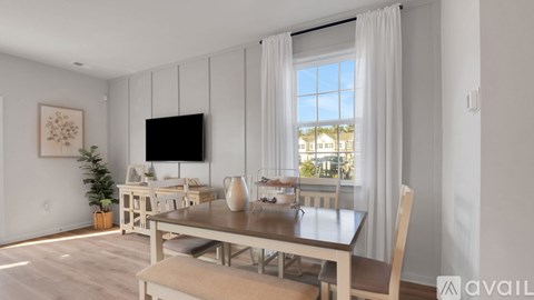 A dining room with a table set for four and a television mounted on the wall.