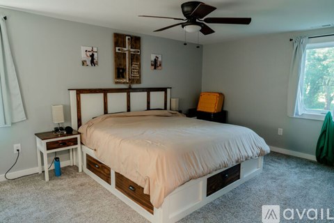 A bedroom with a bed, nightstand, and a fan.