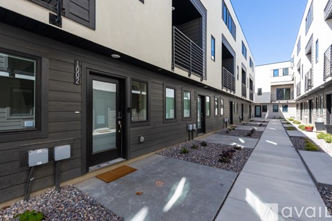 A row of modern townhouses with a sidewalk in front.