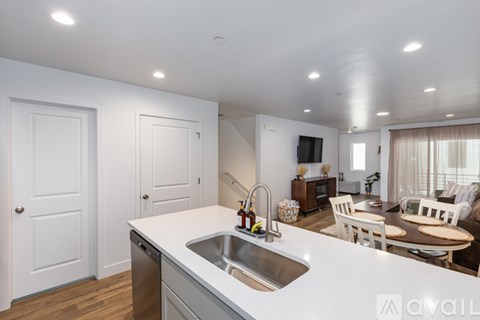 A modern kitchen with a white countertop and a stainless steel sink.