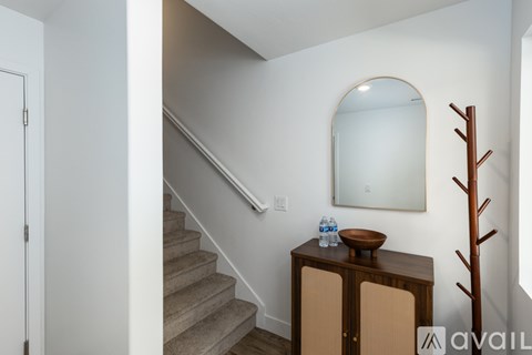 A wooden cabinet with a round table on top is in a room with a staircase.