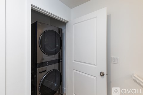 A white door is open to a small kitchen with a black oven and microwave.