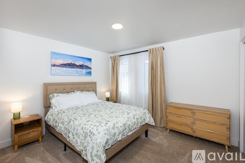 A bedroom with a bed, nightstand, and a painting on the wall.