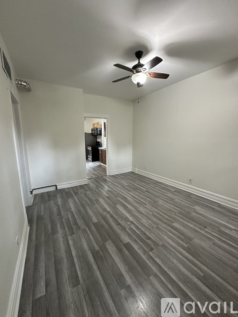 A room with a ceiling fan and wooden flooring.