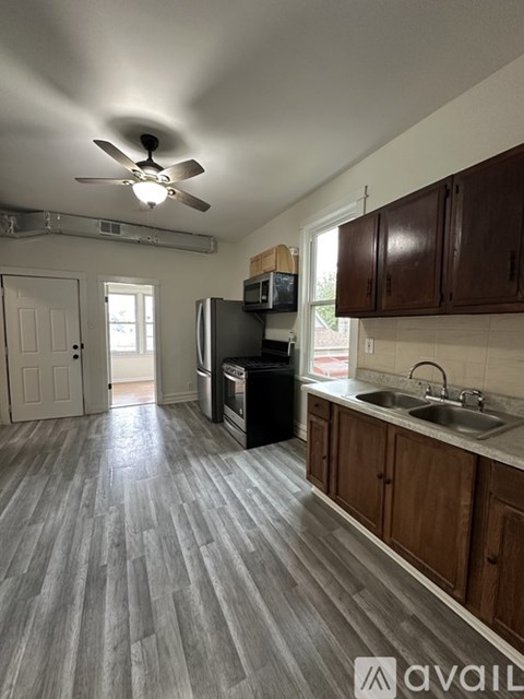 A kitchen with wooden cabinets and a black refrigerator.