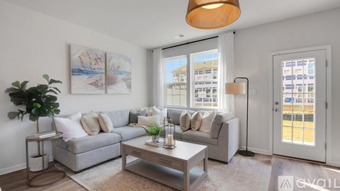 A living room with a grey couch, a coffee table, and a large window with a view of a building outside.