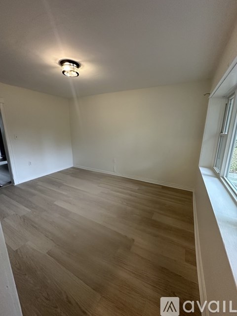 A room with wooden flooring and a window on the right side.