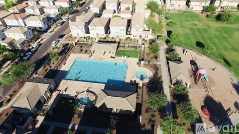 An aerial view of a swimming pool surrounded by houses and greenery.