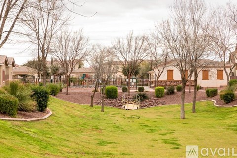 A playground with a swing set in the middle of a grassy area.