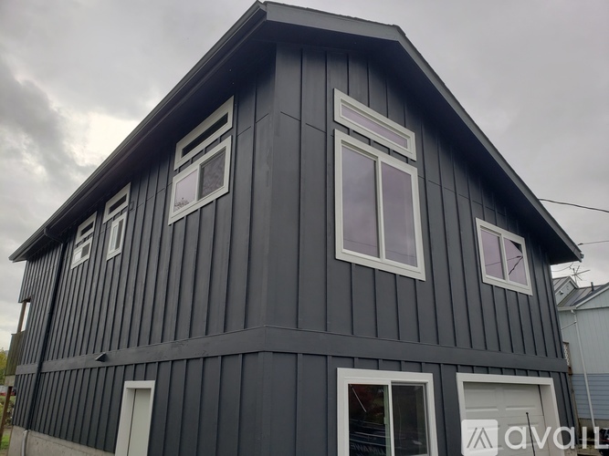 A wooden house with a grey exterior and white windows.