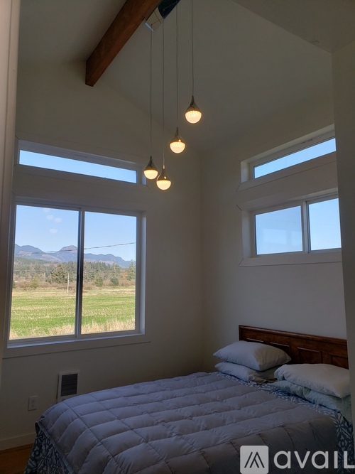 A bedroom with a large bed and a view of the outdoors through the windows.