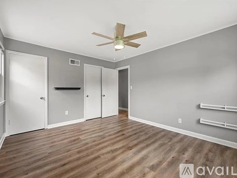 A spacious room with a ceiling fan and wooden flooring.