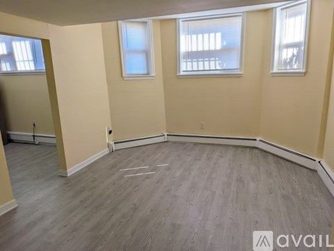 A room with wooden flooring and two windows.