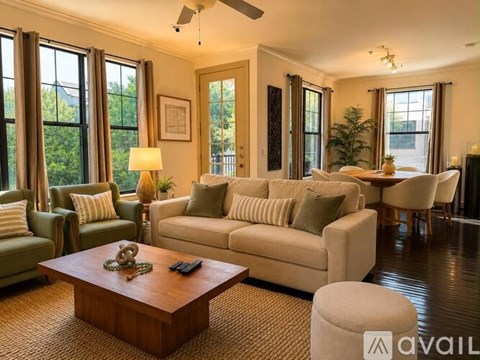 A living room with a large couch, a coffee table, and a ceiling fan.