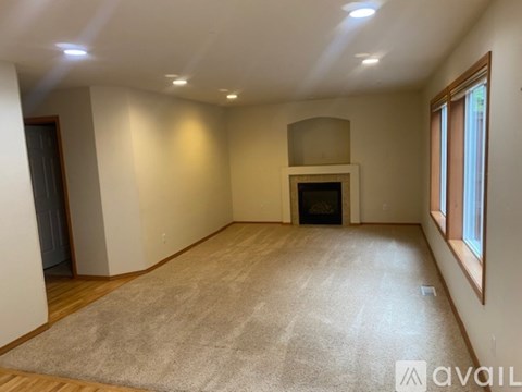 A spacious living room with a fireplace and a carpet on the floor.