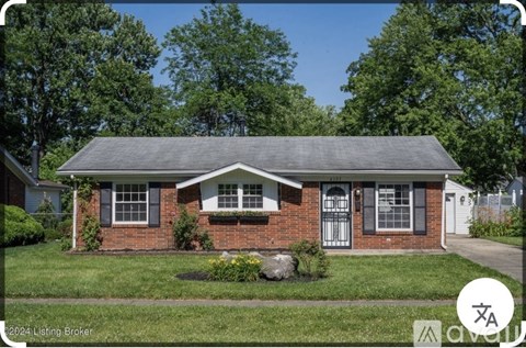 A house with a brick facade and a grey roof is surrounded by greenery.
