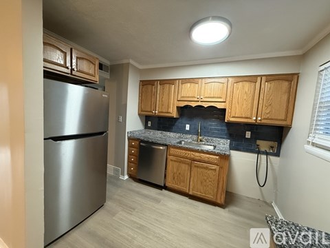 A kitchen with a stainless steel refrigerator and wooden cabinets.