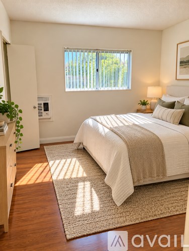 A bedroom with a bed, a window, and a plant.