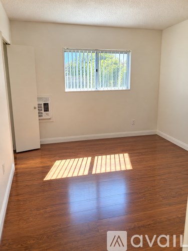 A room with wooden floors and a window with blinds.