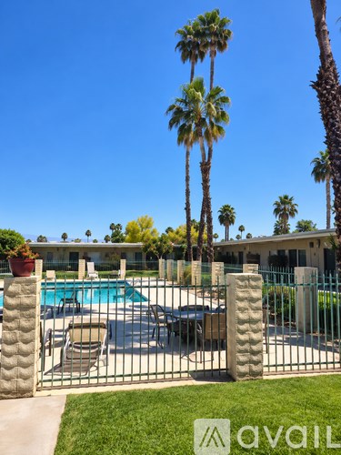 A pool surrounded by a fence with palm trees in the background.