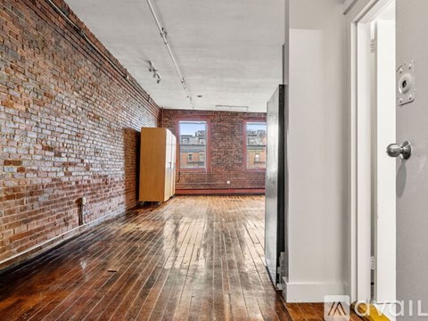 A room with a wooden floor and a brick wall.
