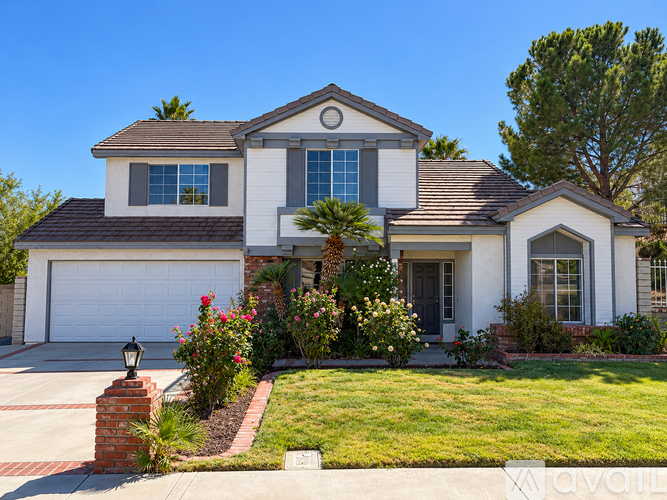 A white house with a brown roof and a grey garage door.