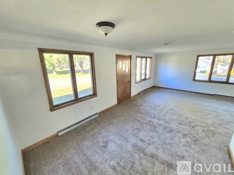 A spacious room with a carpeted floor and large windows.