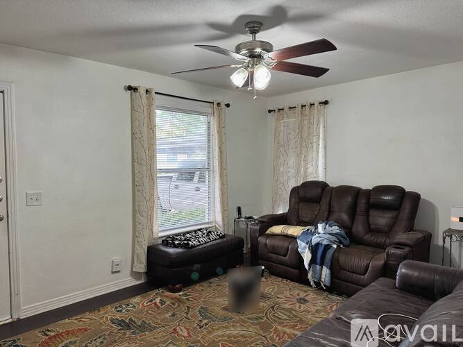 A living room with a brown leather couch and a ceiling fan.