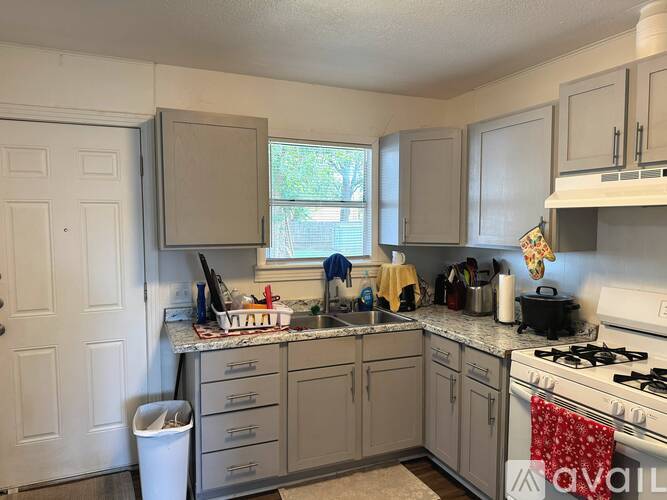 A kitchen with a white stove top oven and a white trash can.