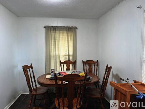 A dining room with a round wooden table surrounded by chairs.