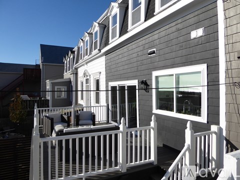 A grey house with a white fence and a small patio area.
