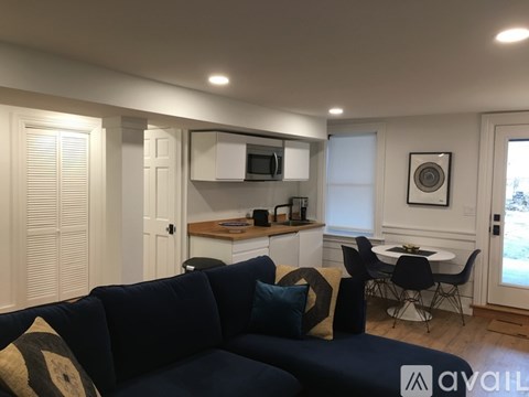 A living room with a dark blue couch and a small dining table.
