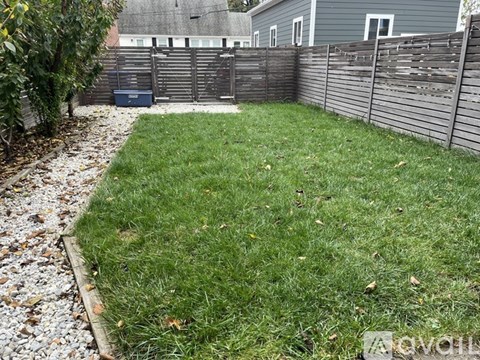 A backyard with a wooden fence and a gravel path.