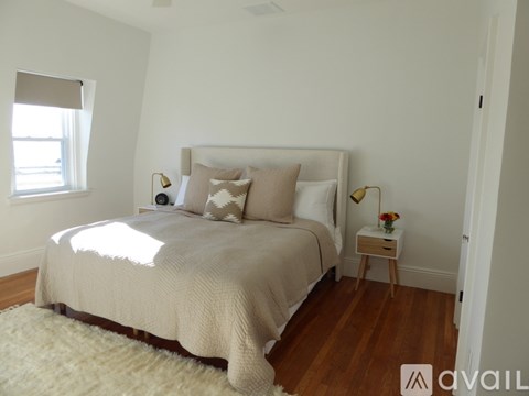 A bedroom with a large bed and a small table with a vase of flowers on it.