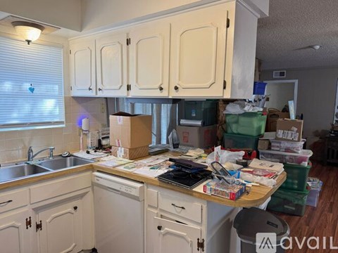 A kitchen with white cabinets and a messy counter.