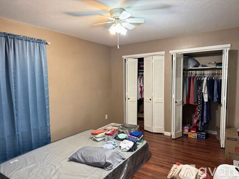 A bedroom with a bed, closet, and a ceiling fan.