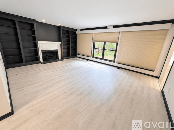 A spacious room with a fireplace and wooden flooring.