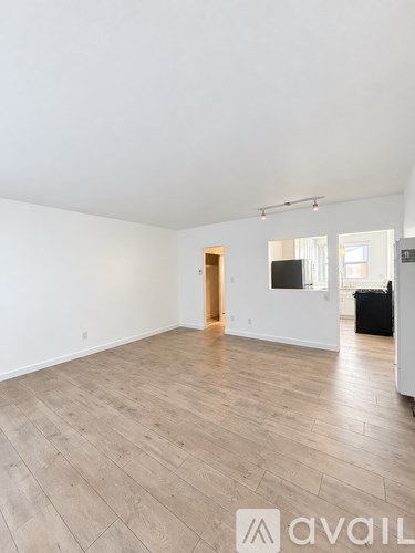 A spacious room with wooden flooring and a doorway leading to another room.